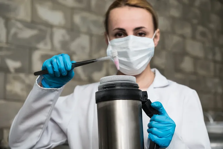 Wissenschaftlerin entnimmt eine Probe aus einem Cryo-Behälter